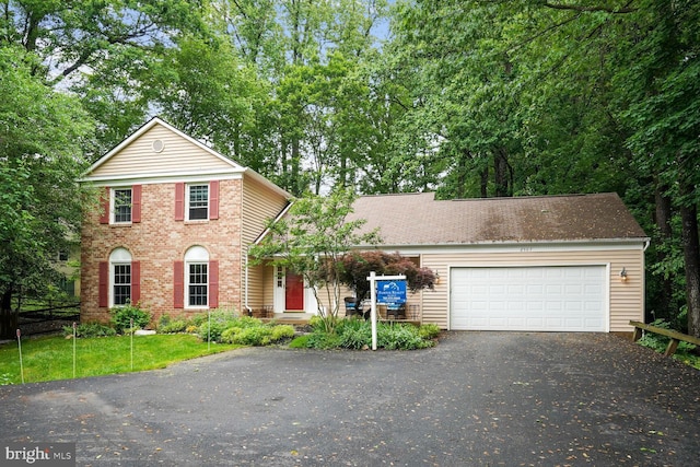 view of front of home featuring driveway, an attached garage, and brick siding