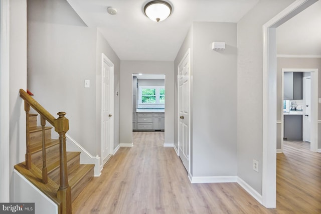 hallway featuring light wood-type flooring and baseboards