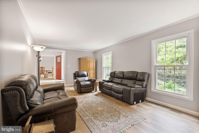 living room featuring healthy amount of natural light, baseboards, light wood-style flooring, and ornamental molding