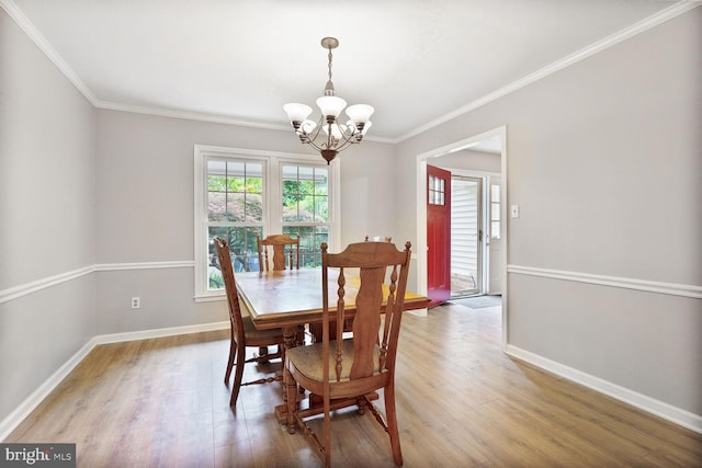 dining space featuring a chandelier, crown molding, wood finished floors, and baseboards