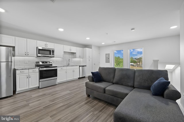 living room with electric panel, light wood-style flooring, and recessed lighting