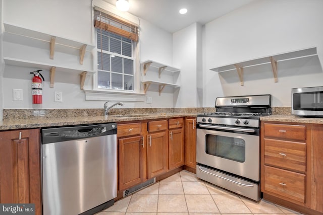 kitchen with open shelves, a sink, brown cabinetry, light tile patterned floors, and appliances with stainless steel finishes