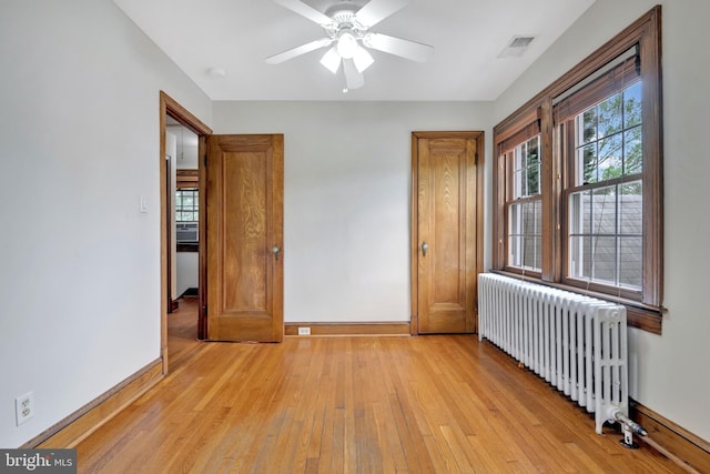 unfurnished bedroom with radiator, light wood-style floors, visible vents, and baseboards