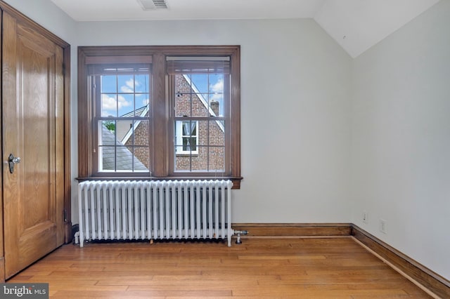 interior space with vaulted ceiling, baseboards, light wood-style floors, and radiator