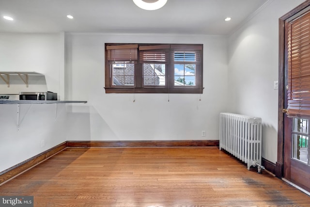 empty room with radiator, baseboards, recessed lighting, hardwood / wood-style floors, and ornamental molding