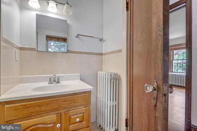 bathroom featuring tile walls, a wainscoted wall, vanity, and radiator