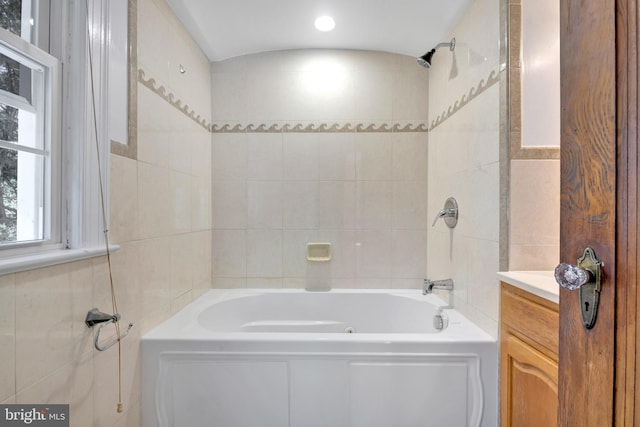 bathroom with tile walls, vanity, and shower / washtub combination