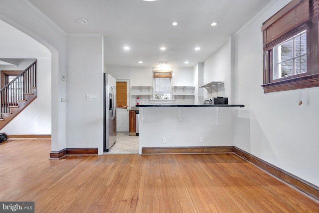 kitchen with light wood finished floors, dark countertops, baseboards, recessed lighting, and stainless steel fridge with ice dispenser