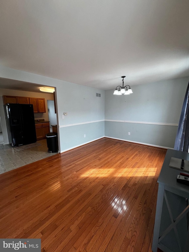 209 Preston Ln, Clayton, DE 19938 - unfurnished living room featuring visible vents, an inviting chandelier, baseboards, and light wood-style floors