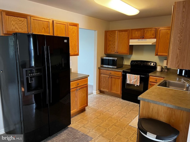 209 Preston Ln, Clayton, DE 19938 - kitchen with light floors, under cabinet range hood, black appliances, dark countertops, and a sink