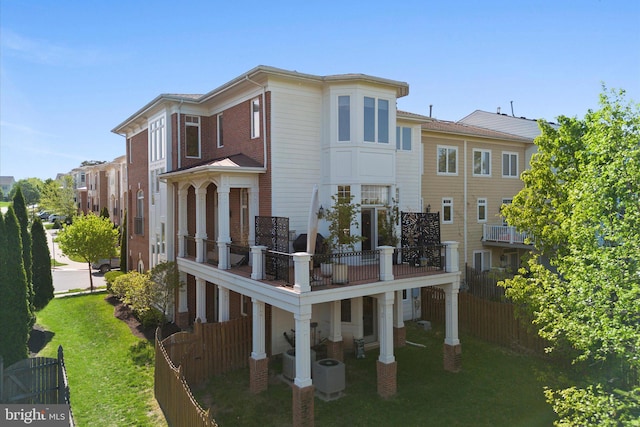 back of property with fence, a balcony, and a lawn