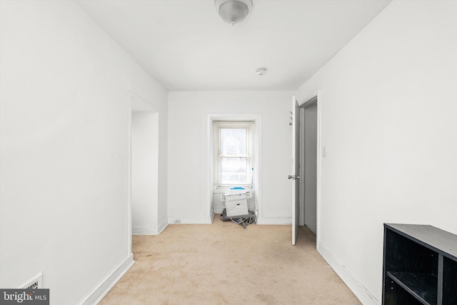 interior space with baseboards and light carpet