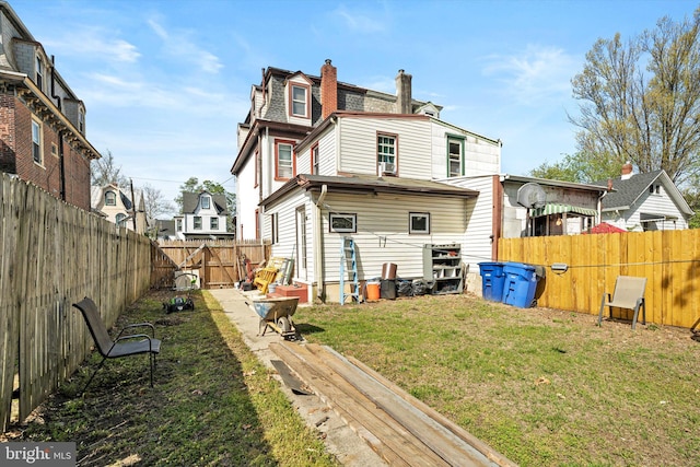 back of house featuring a chimney, a fenced backyard, a residential view, and a yard