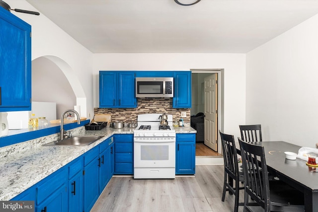 kitchen with stainless steel microwave, decorative backsplash, a sink, blue cabinetry, and white gas stove