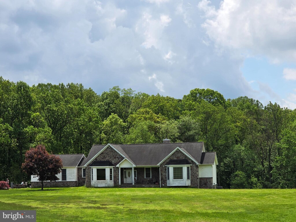 ranch-style house featuring a front lawn and a view of trees