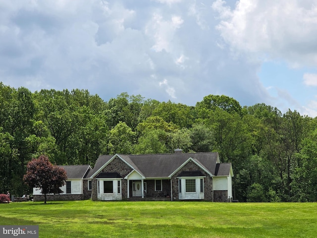 ranch-style house featuring a front lawn and a view of trees
