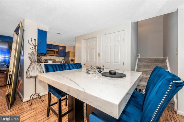 558 Hollyberry Way, Frederick, MD 21703 - dining area featuring light wood-style floors, baseboards, stairs, and a textured ceiling