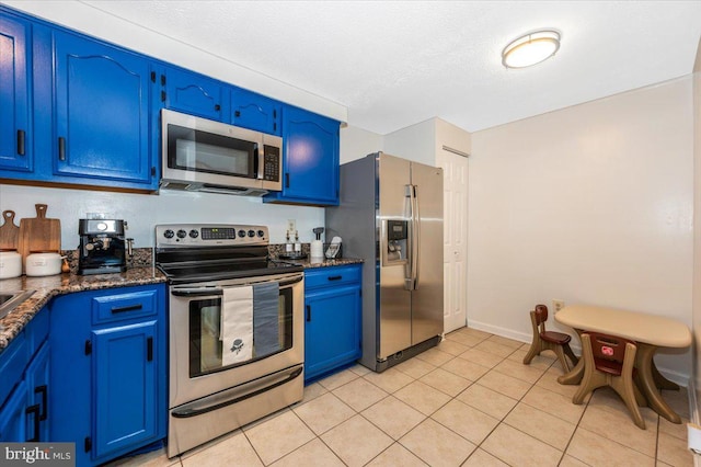 558 Hollyberry Way, Frederick, MD 21703 - kitchen featuring blue cabinetry, appliances with stainless steel finishes, light tile patterned floors, baseboards, and dark stone counters
