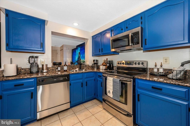 558 Hollyberry Way, Frederick, MD 21703 - kitchen featuring blue cabinetry, appliances with stainless steel finishes, light tile patterned floors, and dark stone countertops