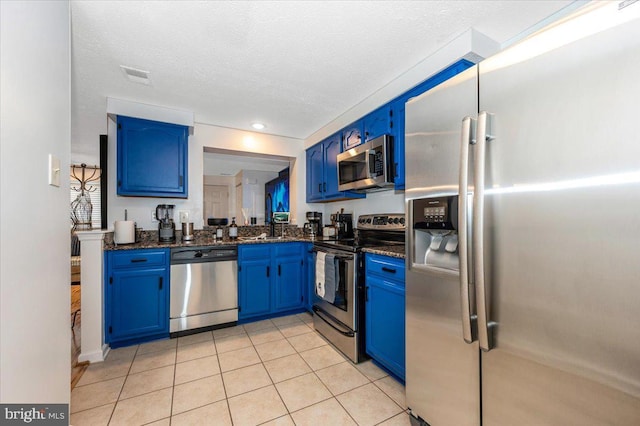 558 Hollyberry Way, Frederick, MD 21703 - kitchen with dark stone counters, a textured ceiling, blue cabinets, light tile patterned floors, and stainless steel appliances