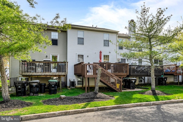 back of house featuring a lawn, a wooden deck, stairs, and a chimney