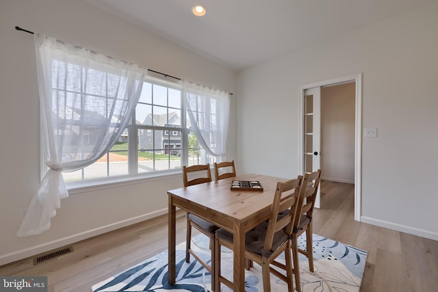 dining room with baseboards, visible vents, and light wood finished floors