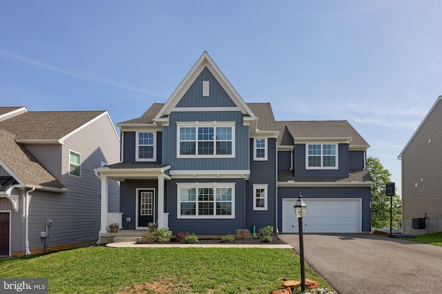 craftsman-style home with board and batten siding, an attached garage, a front yard, and aphalt driveway