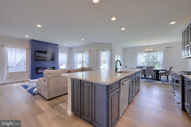 kitchen featuring light wood-type flooring, light countertops, a chandelier, a sink, and appliances with stainless steel finishes