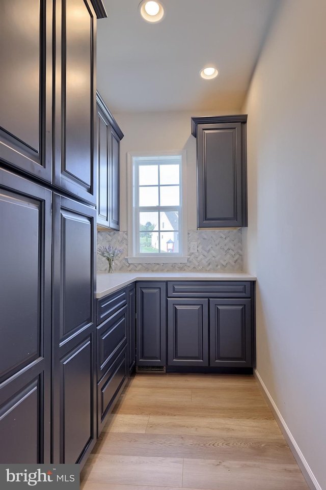 kitchen with recessed lighting, light countertops, light wood finished floors, and tasteful backsplash