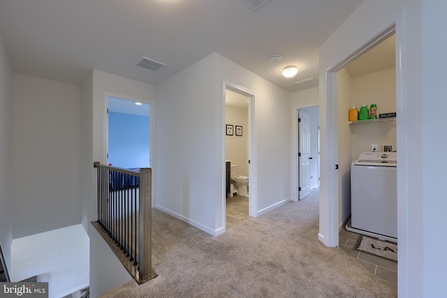 hallway with carpet floors, washer / clothes dryer, baseboards, an upstairs landing, and visible vents