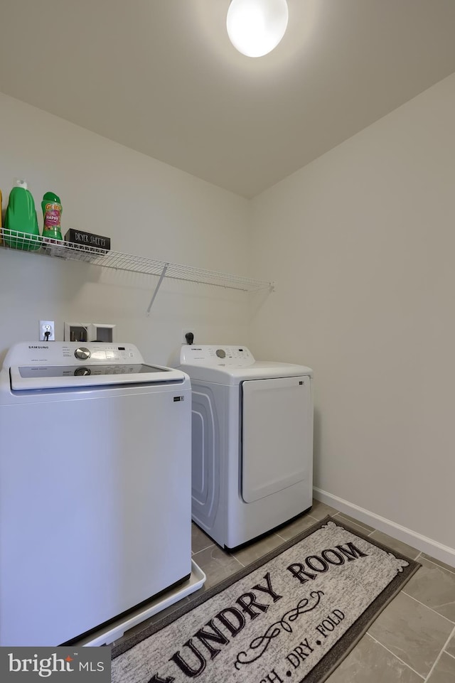 laundry room with laundry area, washer and clothes dryer, baseboards, and tile patterned floors