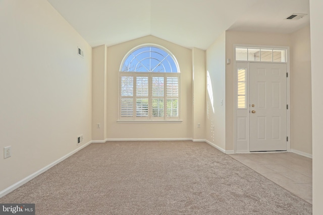tiled foyer with lofted ceiling, visible vents, and carpet