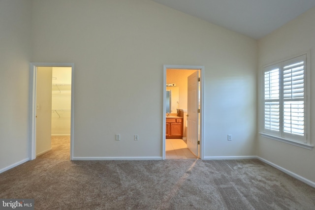 unfurnished bedroom with a spacious closet, a closet, baseboards, carpet flooring, and high vaulted ceiling