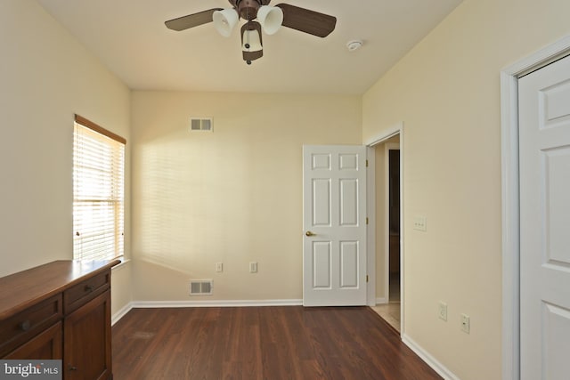 unfurnished bedroom with dark wood-type flooring, visible vents, and baseboards