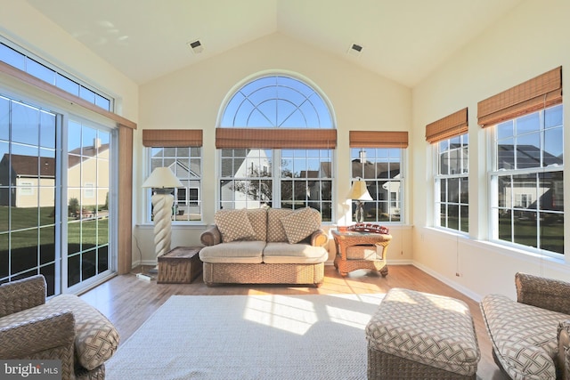 sunroom featuring vaulted ceiling, wood finished floors, visible vents, and baseboards