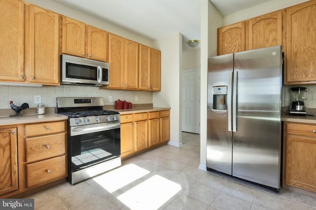 kitchen with backsplash, light tile patterned floors, appliances with stainless steel finishes, and light countertops