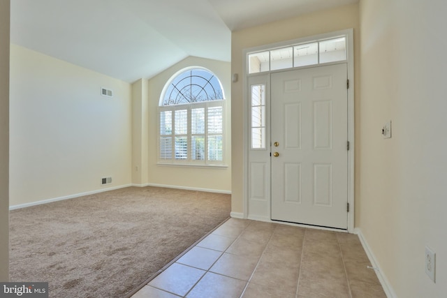 entryway featuring vaulted ceiling, visible vents, light carpet, light tile patterned flooring, and baseboards