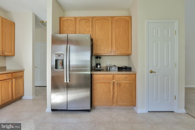 kitchen featuring light countertops, stainless steel refrigerator with ice dispenser, and baseboards
