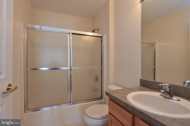 bathroom with vanity, enclosed tub / shower combo, and toilet
