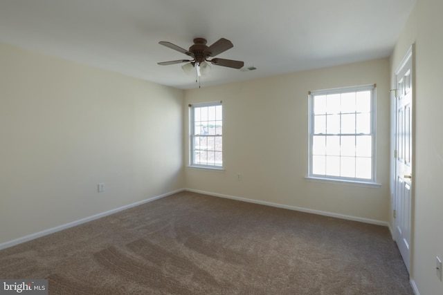 spare room with carpet, visible vents, a ceiling fan, and baseboards