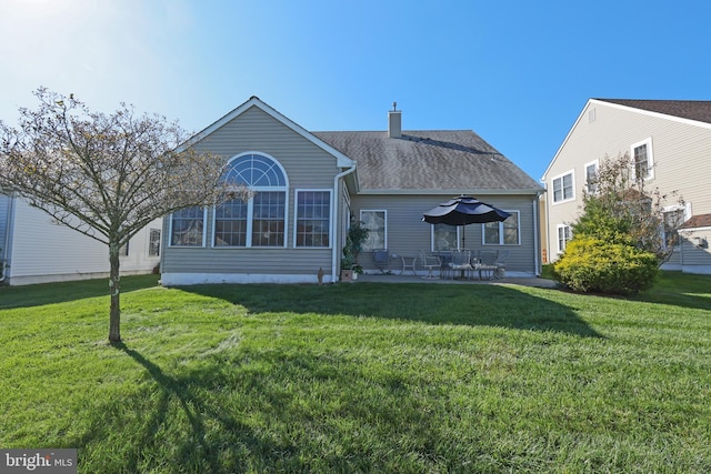 rear view of house featuring a lawn, a chimney, and a patio