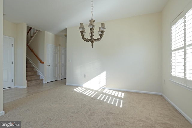 carpeted empty room with baseboards, stairs, a chandelier, and a wealth of natural light