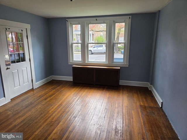 spare room with baseboards, plenty of natural light, and hardwood / wood-style flooring