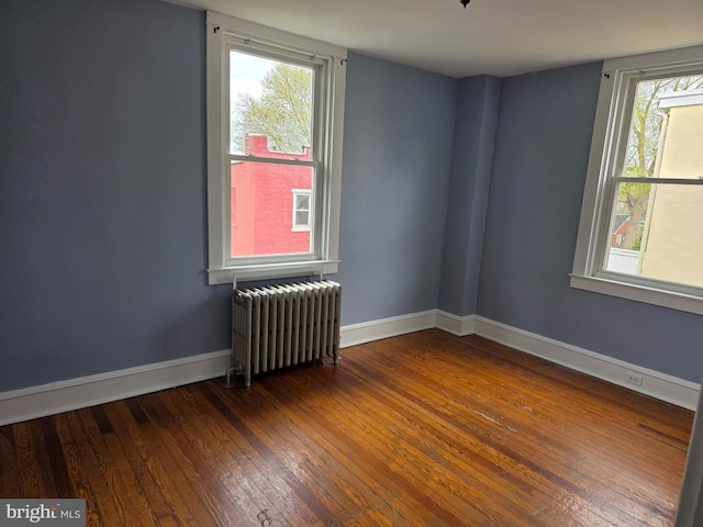 spare room with radiator heating unit, hardwood / wood-style flooring, baseboards, and a healthy amount of sunlight