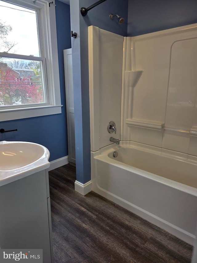 full bathroom featuring wood finished floors, vanity, baseboards, and shower / washtub combination