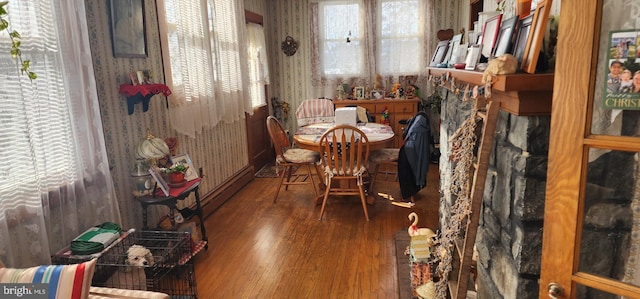 dining room with wallpapered walls, wood finished floors, and baseboard heating