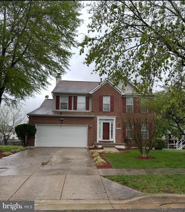 view of front of home featuring a chimney, a front lawn, concrete driveway, an attached garage, and brick siding