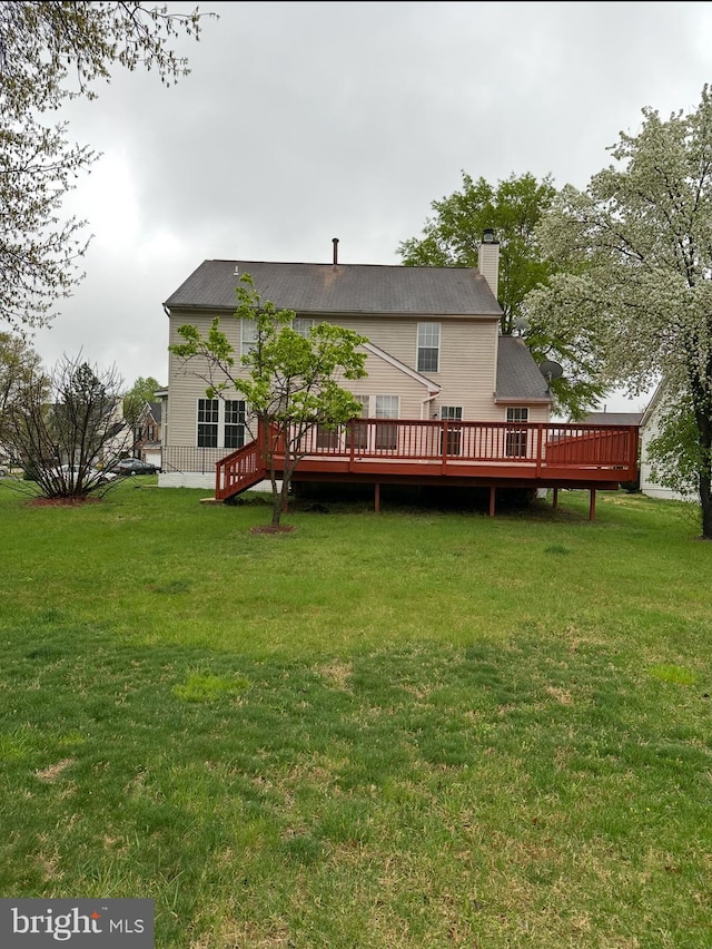 rear view of house featuring a yard, a chimney, and a deck