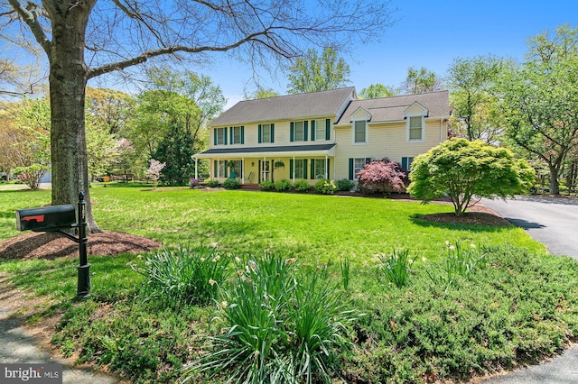 colonial home with covered porch and a front lawn