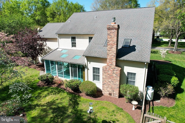 back of property with a yard, roof with shingles, a chimney, and a sunroom